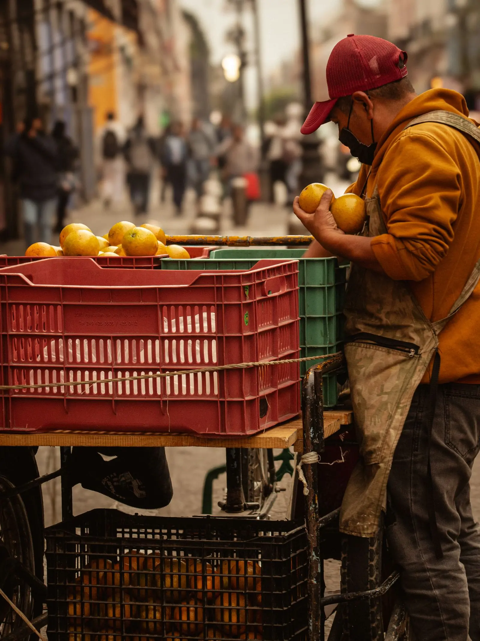 Vendedor ambulante acomodando cajas de naranjas en su carrito en el centro de Puebla, México.