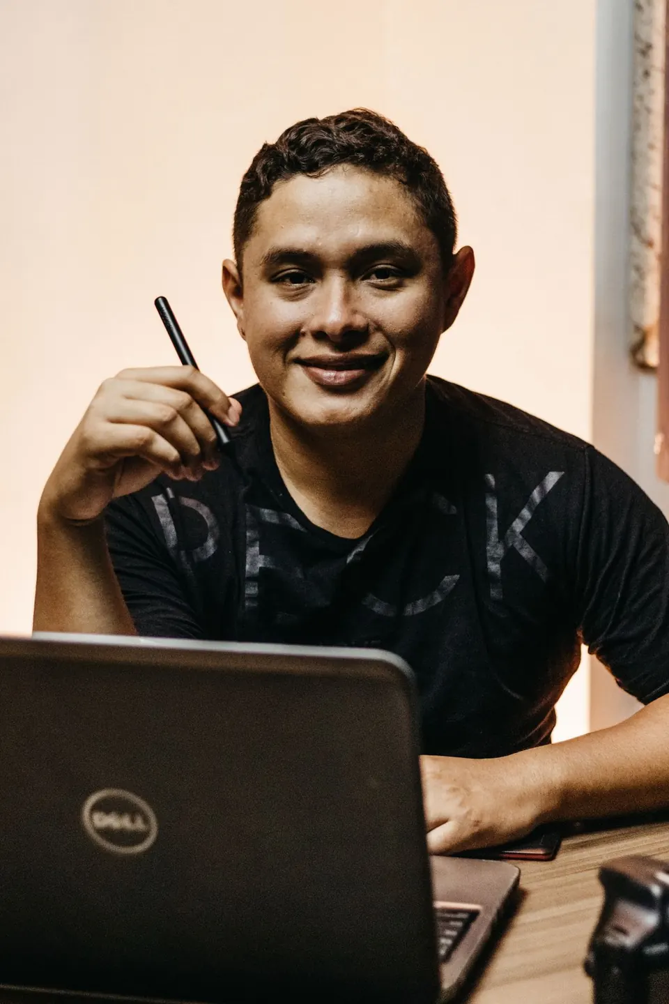 Hombre sonriendo mientras trabaja en su laptop, tomando notas.