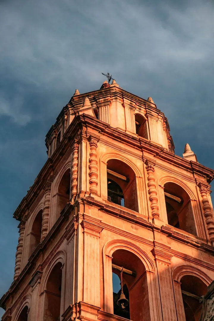 Torre de cantera de una iglesia colonial en el centro de San Luis Potosí, iluminada al atardecer.